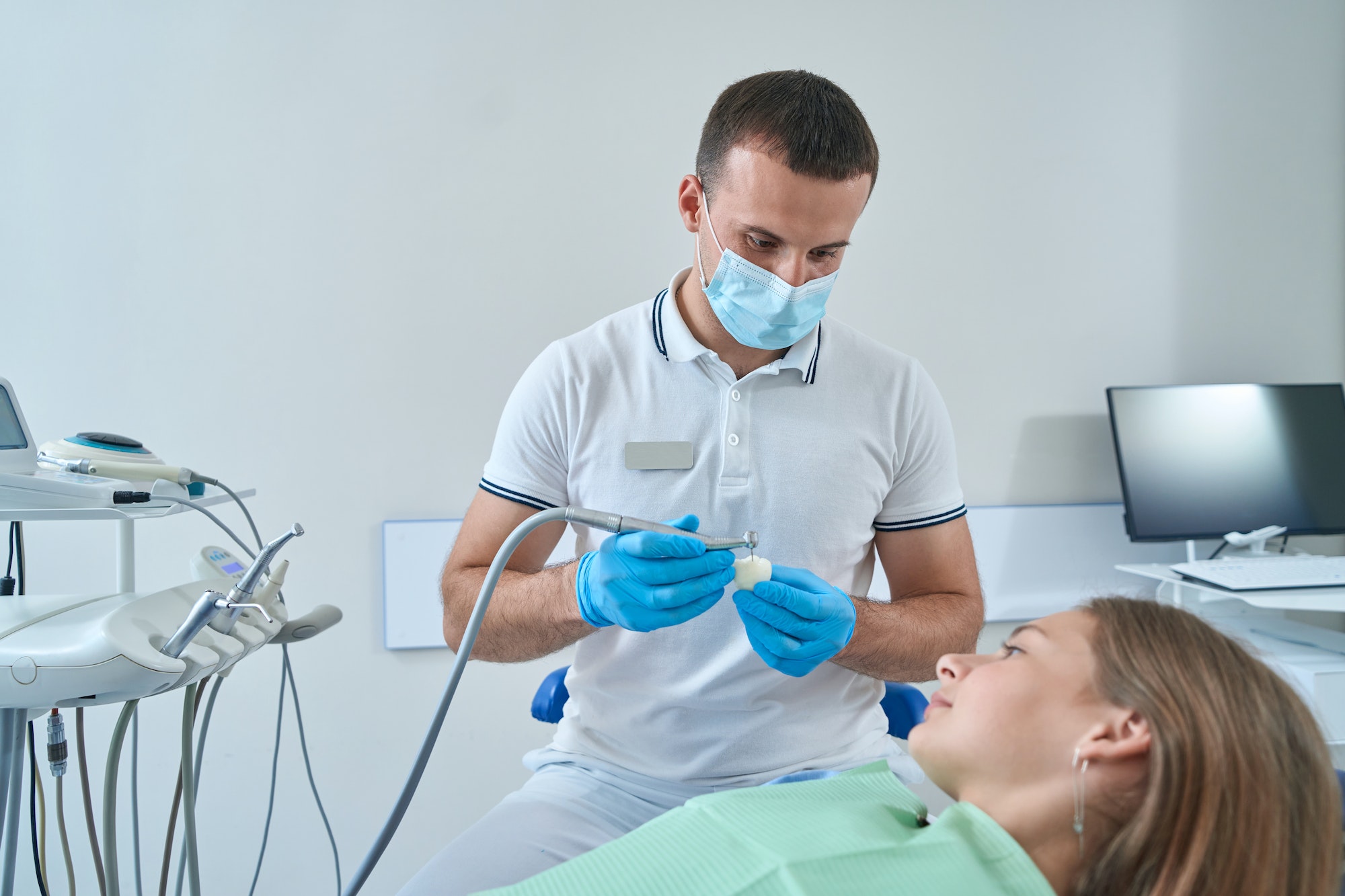 Serious focused pedodontist performing tooth restoration procedure