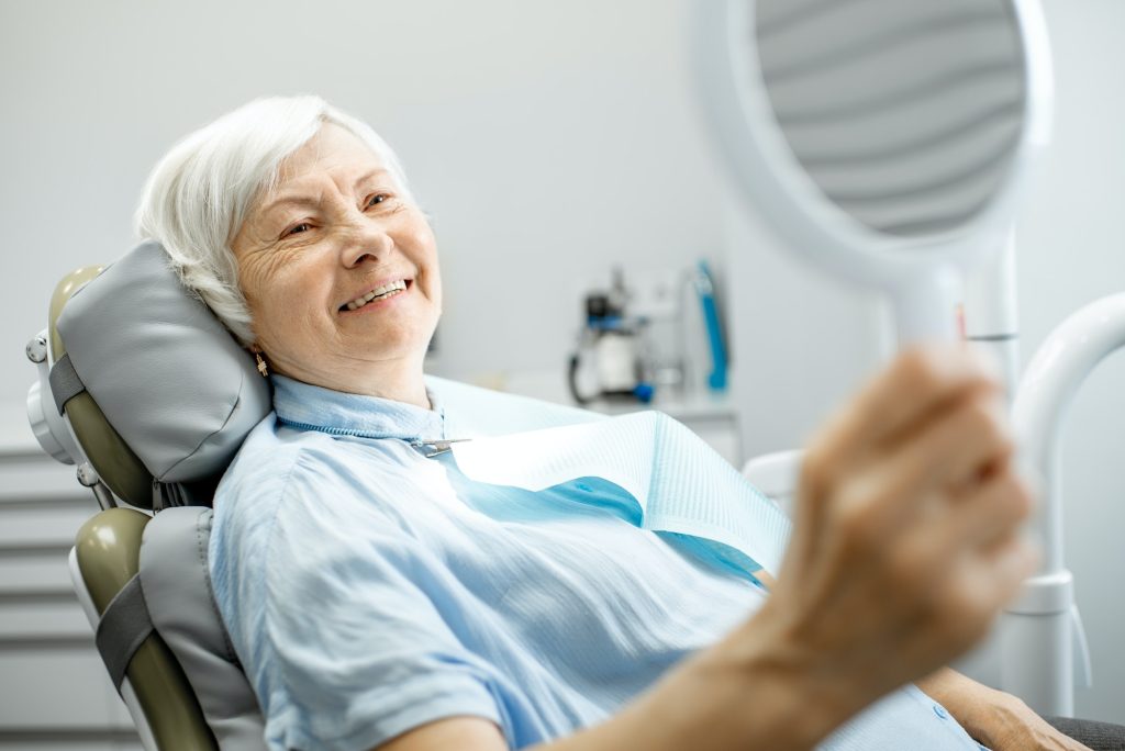 Elderly woman enjoying her smile in the dental office